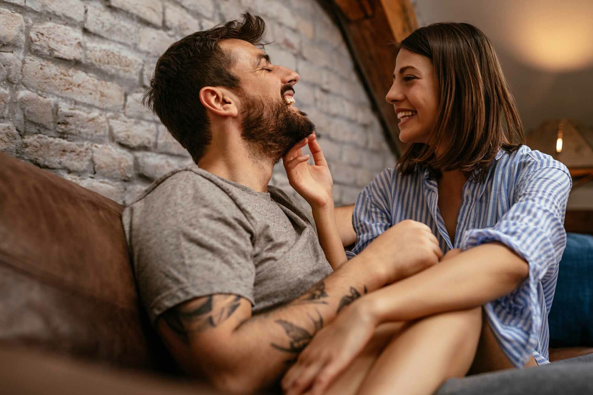 Playful Couple Cuddles on Couch Laughing at Bad Dating Advice