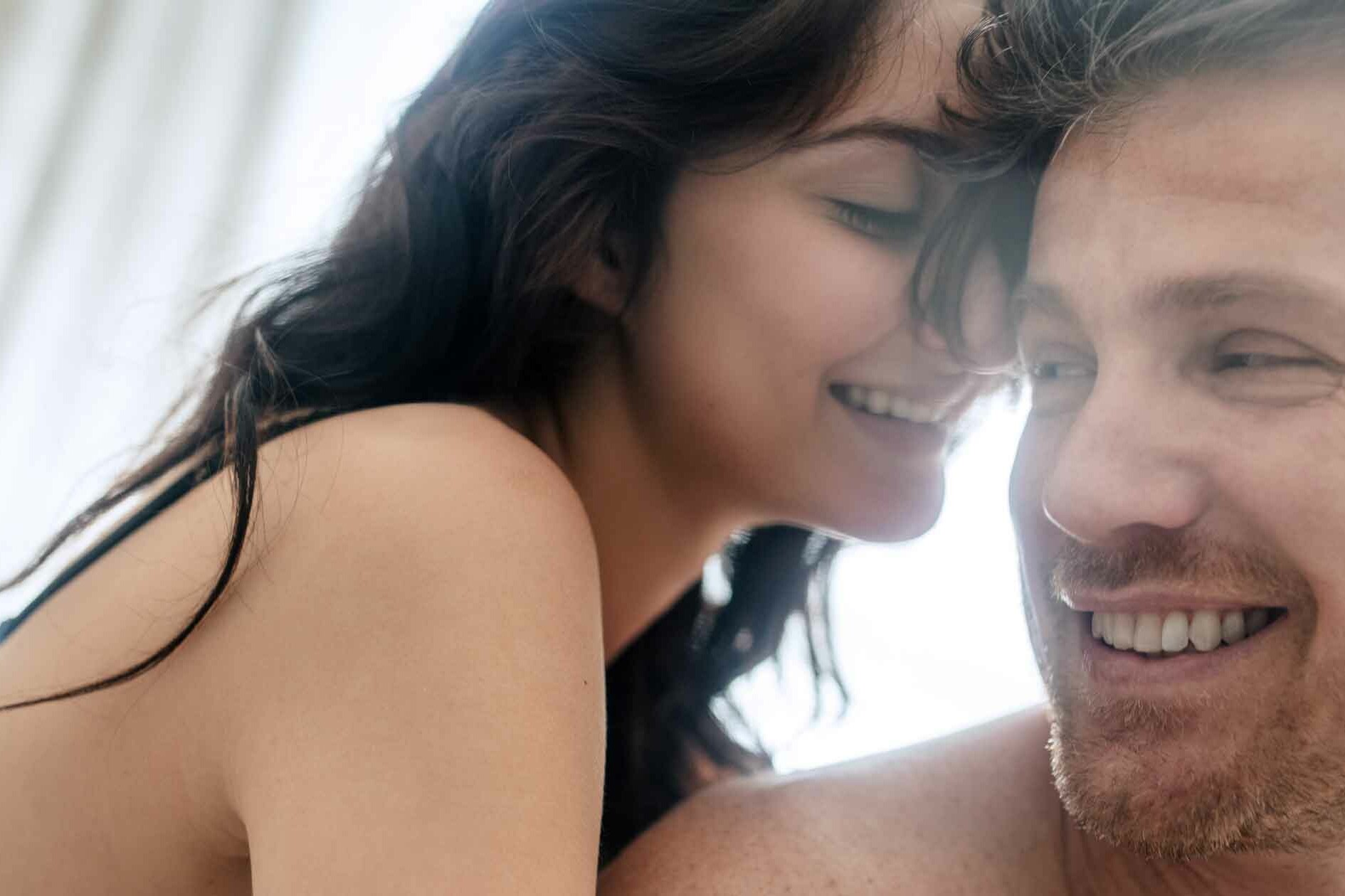 Couple in Bed Together Sharing Intimacy and Laughing