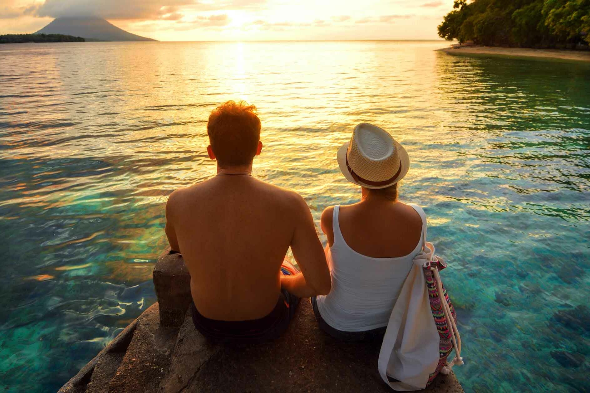 Couple sitting on a rock overlooking a beautiful beach