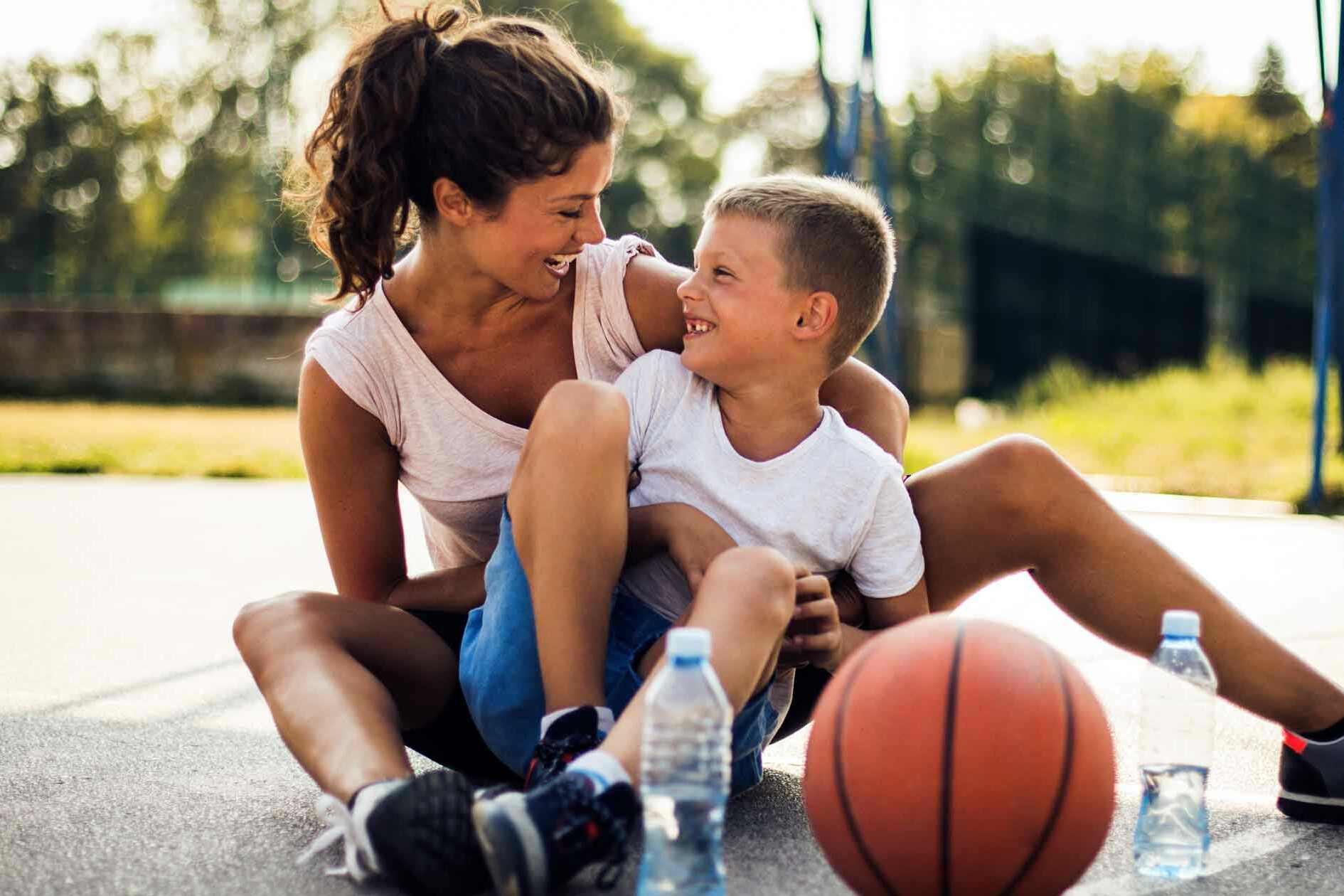 Single Mom and son laughing while on basketball court